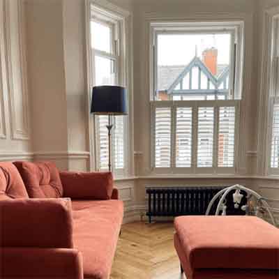 Cafe style window shutters installed in a living room bay window.
