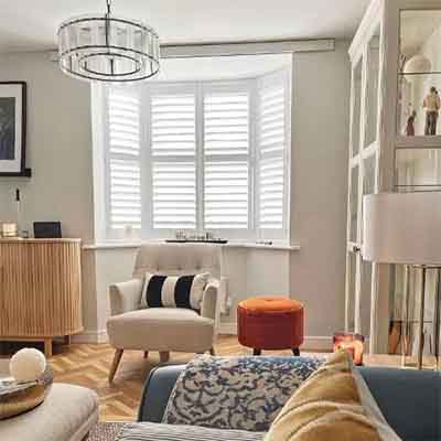 Window shutters installed in a living room bay window.